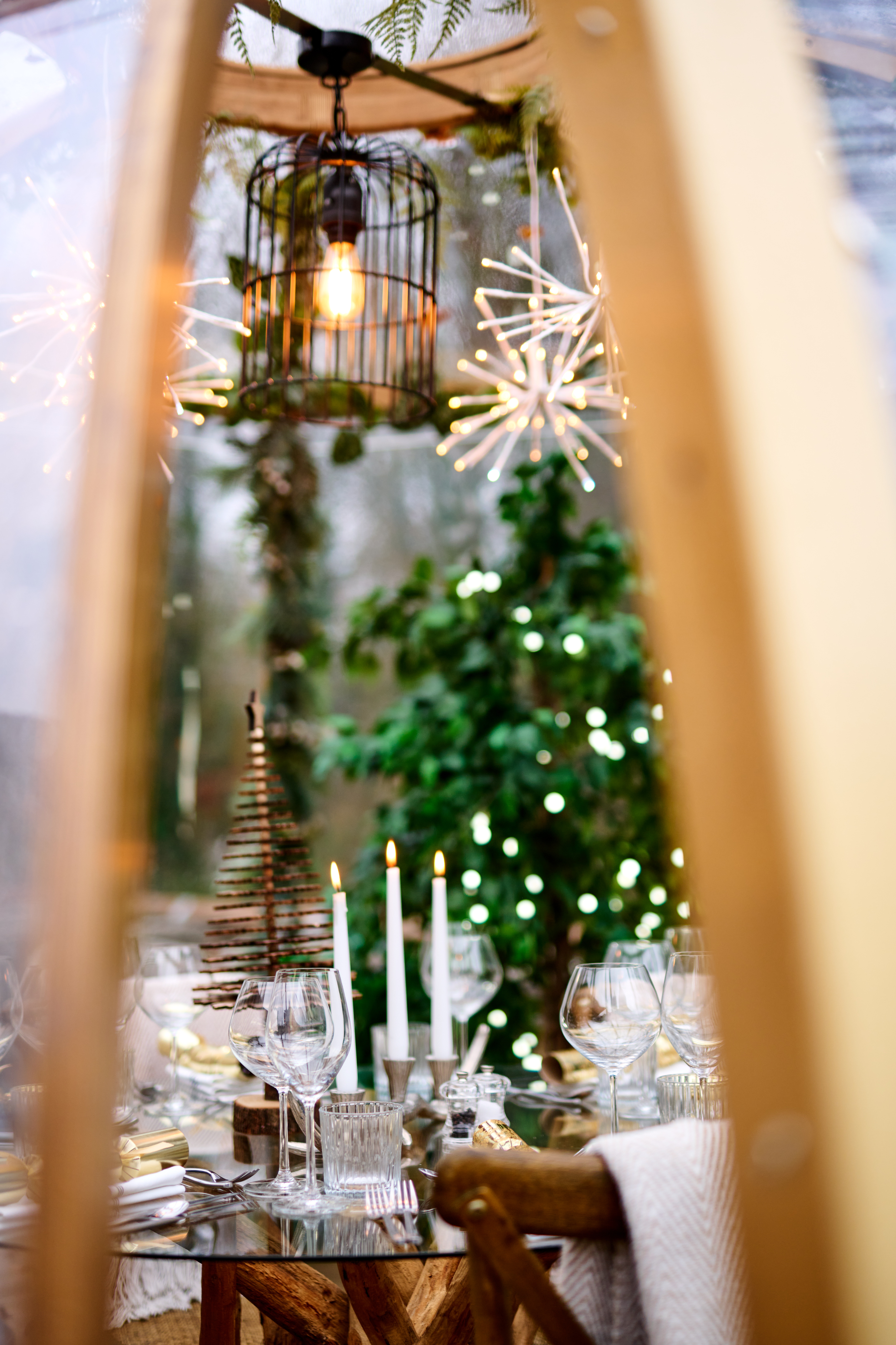 Cozy outdoor dining setup with festive decor, candles, wine glasses, and a Christmas tree adorned with lights. - Wild Thyme & Honey Hotel in the Cotswolds